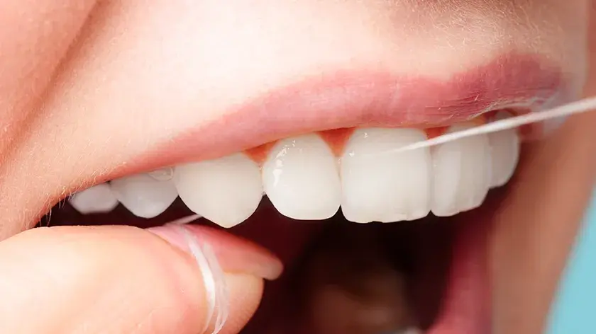 Close-up of a person flossing between their front teeth
