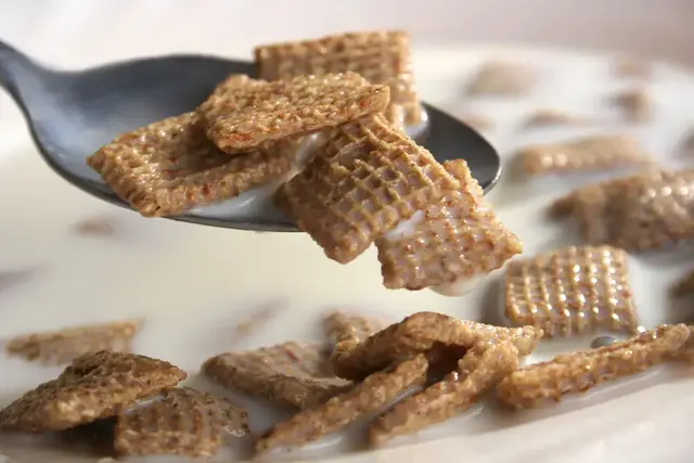 Spoonful of square cereal over a bowl
