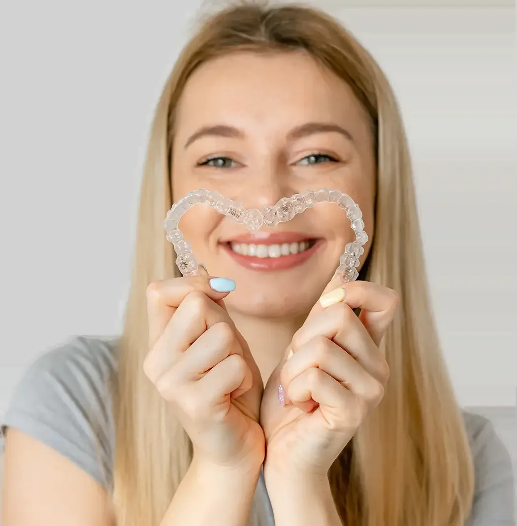 Smiling woman holding a clear aligner