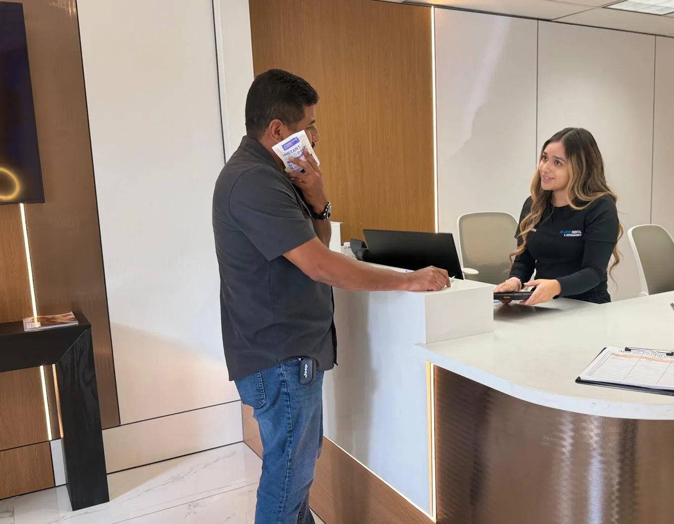 Patient holding an ice pack to his cheek while checking in at our front desk